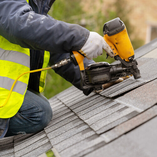roofer nailing down shingles